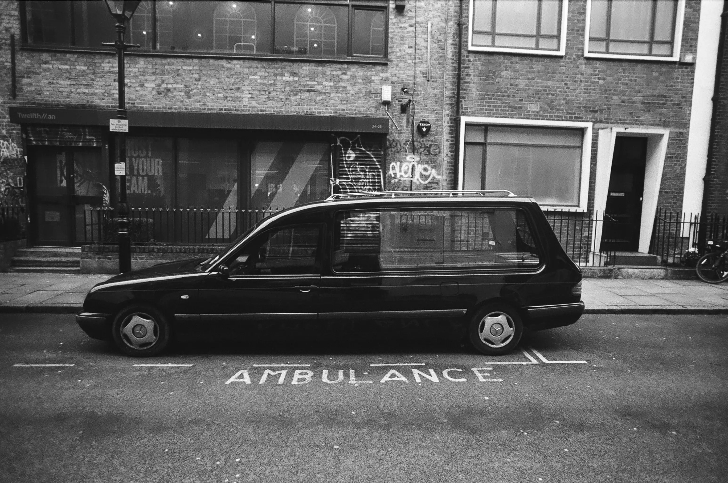 A hearse parked in an ambulance parking spot.