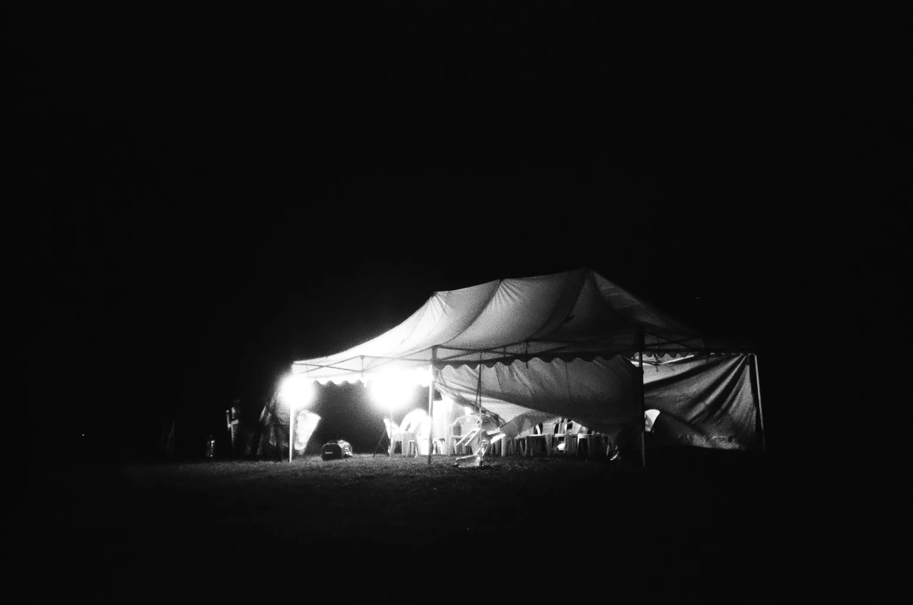 A white tent in a field at night.