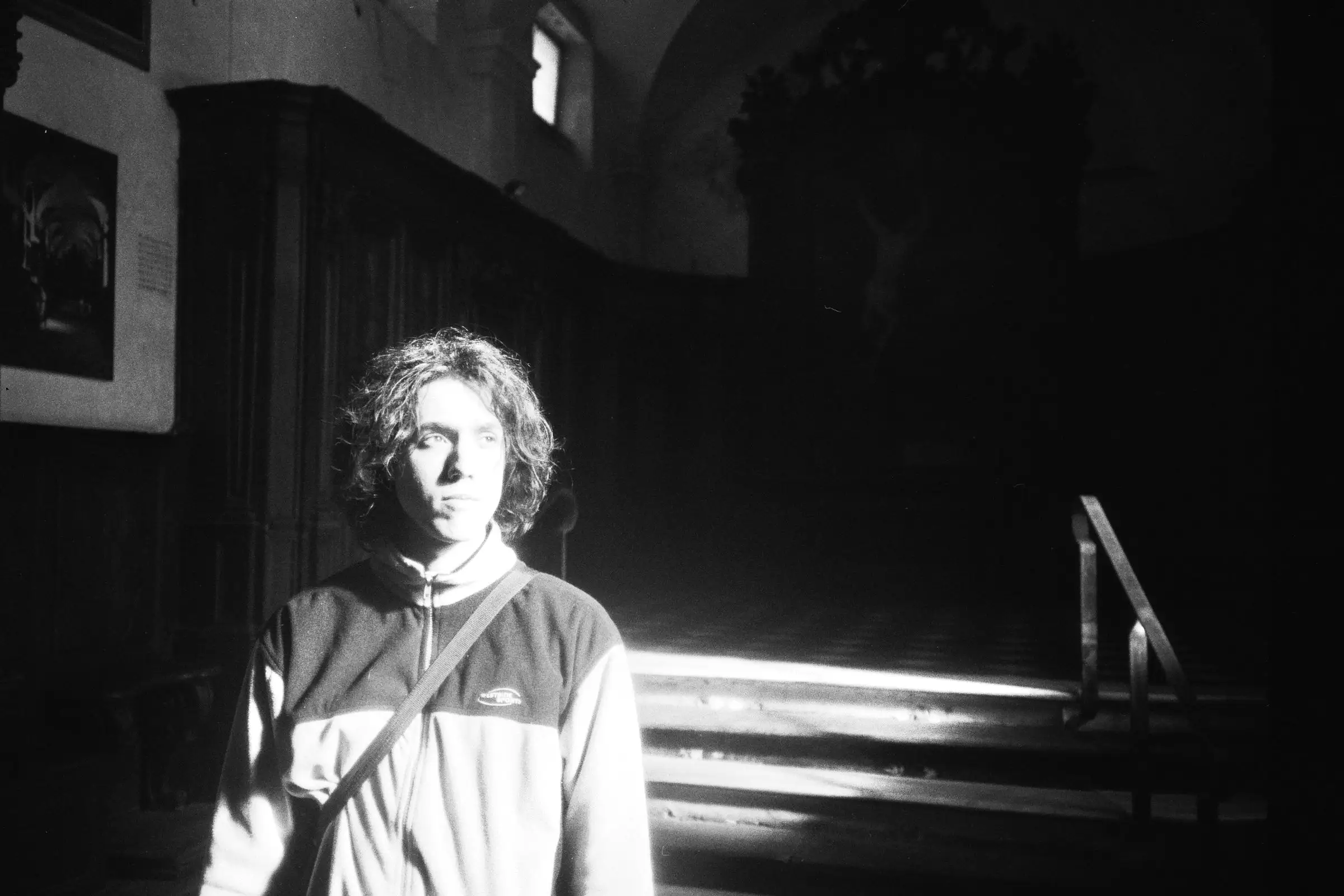 A guy lit by the sun in a church.